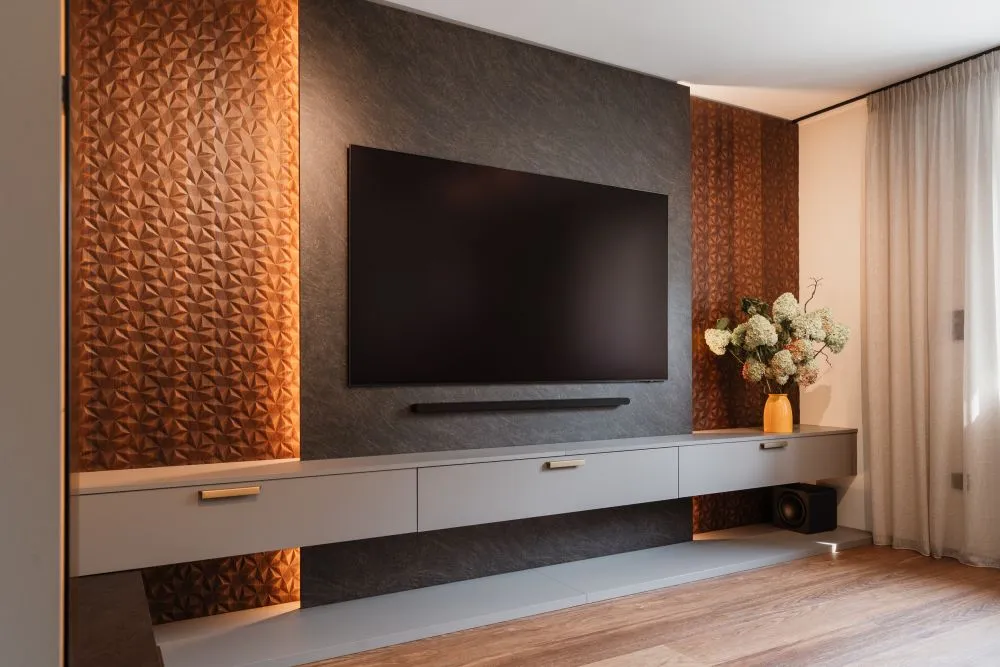 Wandfernseher über einem Sideboard vor strukturierter Wandverkleidung