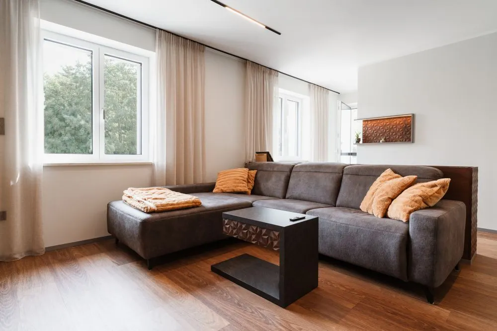 Wohnzimmer mit grauer Polstergarnitur und Couchtisch am Fenster
