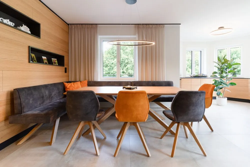 Esszimmer mit Massivholztisch, orangen Stühlen und Sitzbank