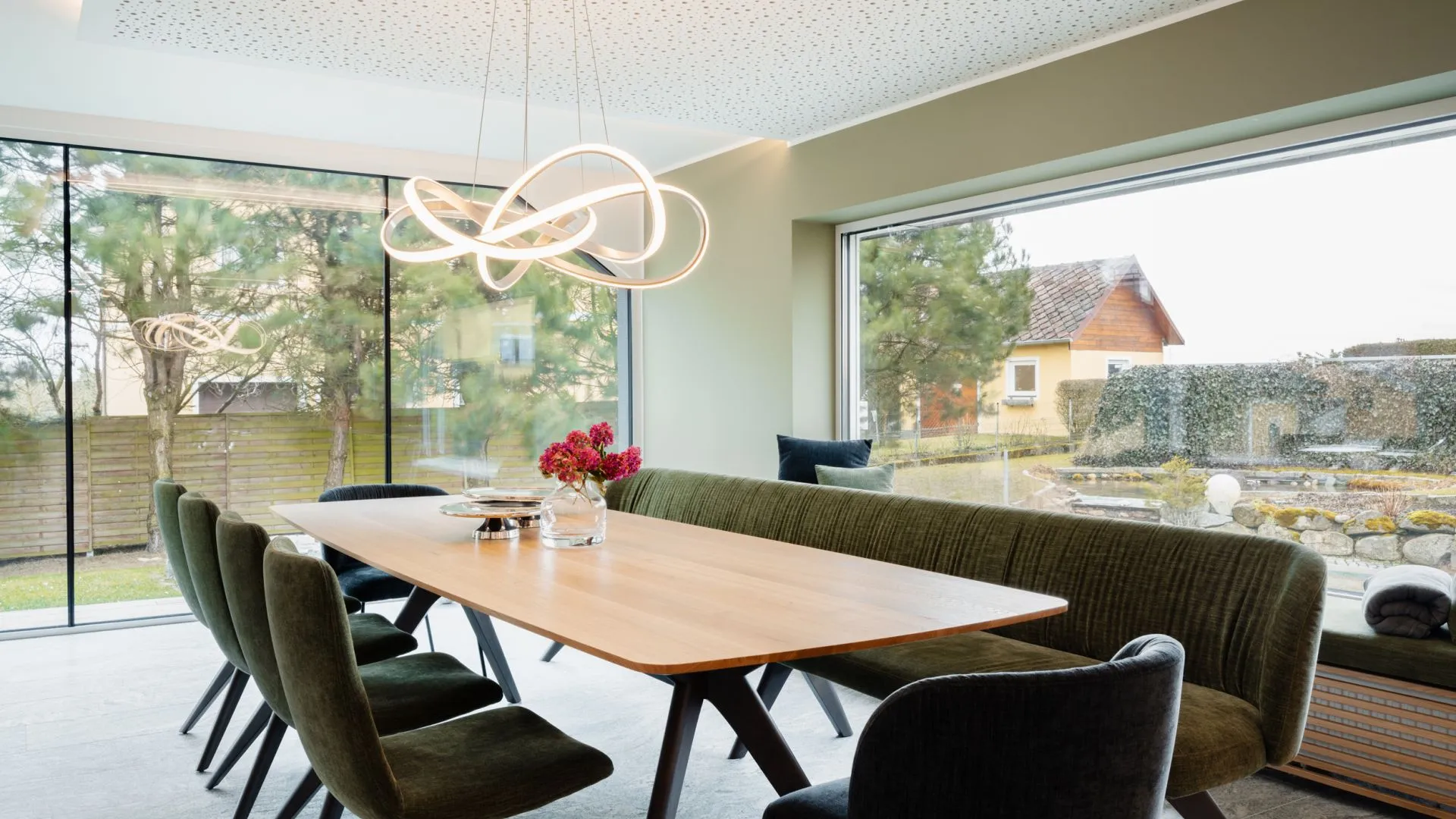 Essbereich mit Holztisch, Designerleuchte und Blick ins Grüne