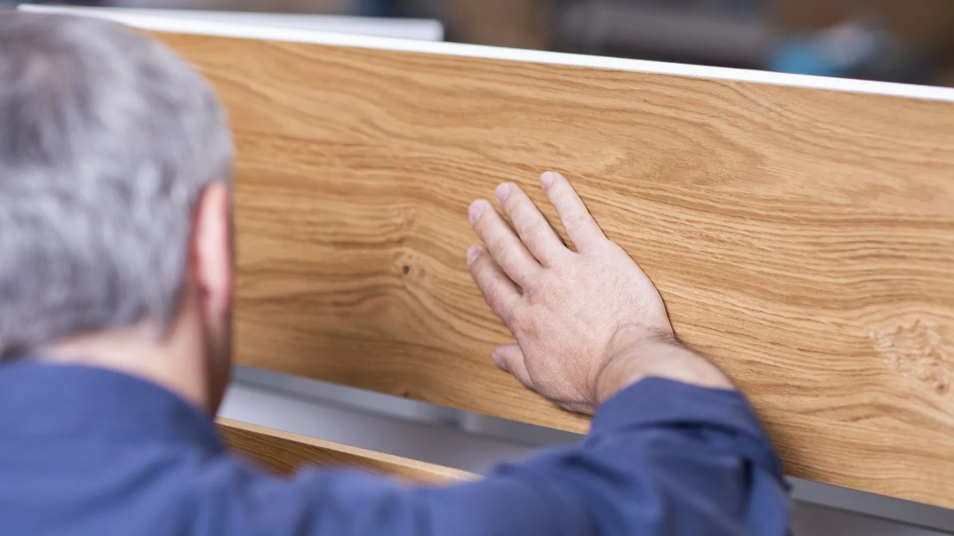 Hand prüft die Oberfläche einer Holzplatte