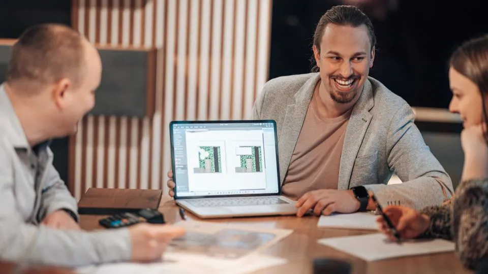 Planungsgespräch am Laptop mit Entwürfen auf dem Tisch