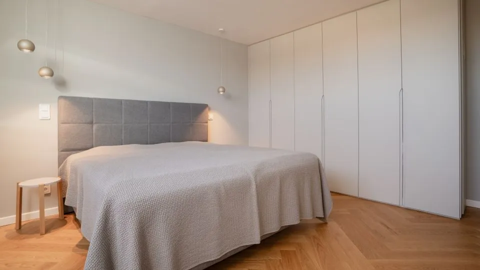 Schlafzimmer mit Doppelbett vor Polsterwand und Einbauschrank