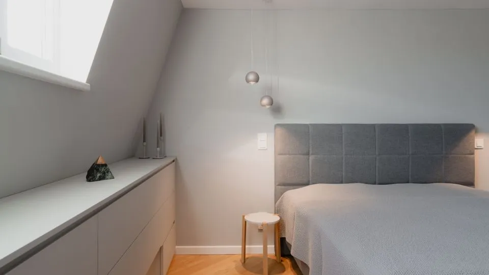Schlafzimmer unter der Dachschräge mit Sideboard und Hocker
