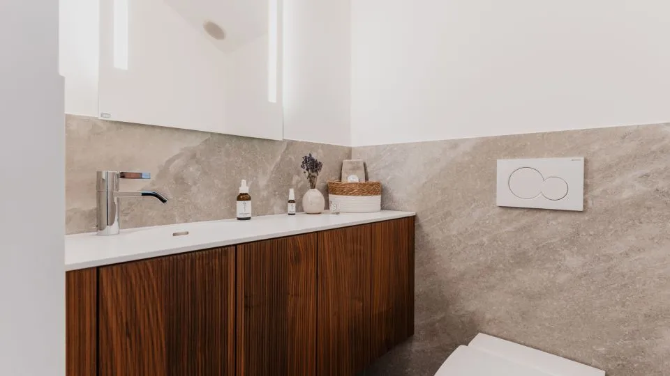 Gäste-WC mit Waschtisch aus dunklem Holz und Steinwand