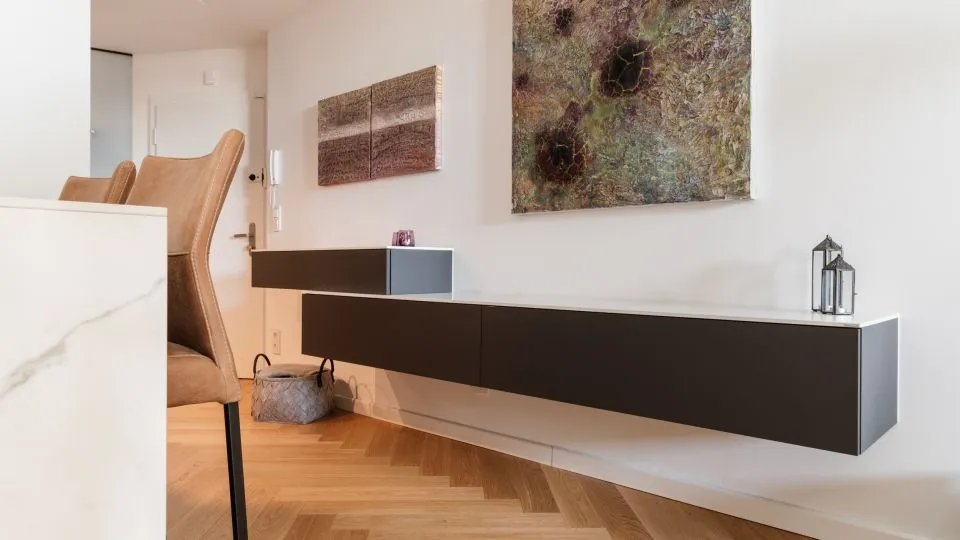 Vorraum mit schwebendem Sideboard, Sessel und Wandbildern