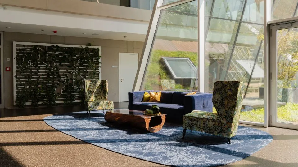 Loungebereich mit dunklem Regal, Sofa und Fensterfront
