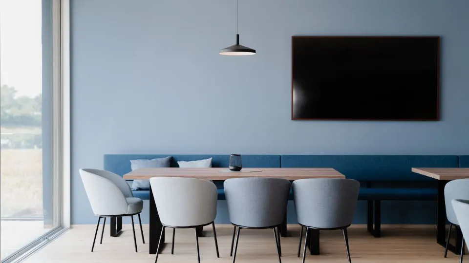 Besprechungsraum mit blauer Wand, Sitzbank und Bildschirm