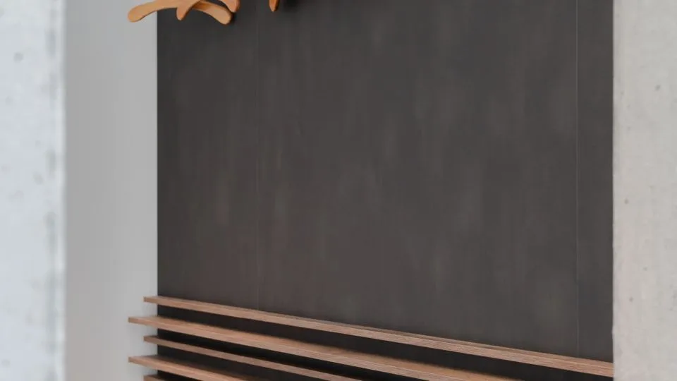 Garderobenwand aus dunklem Filz mit Holzbügeln