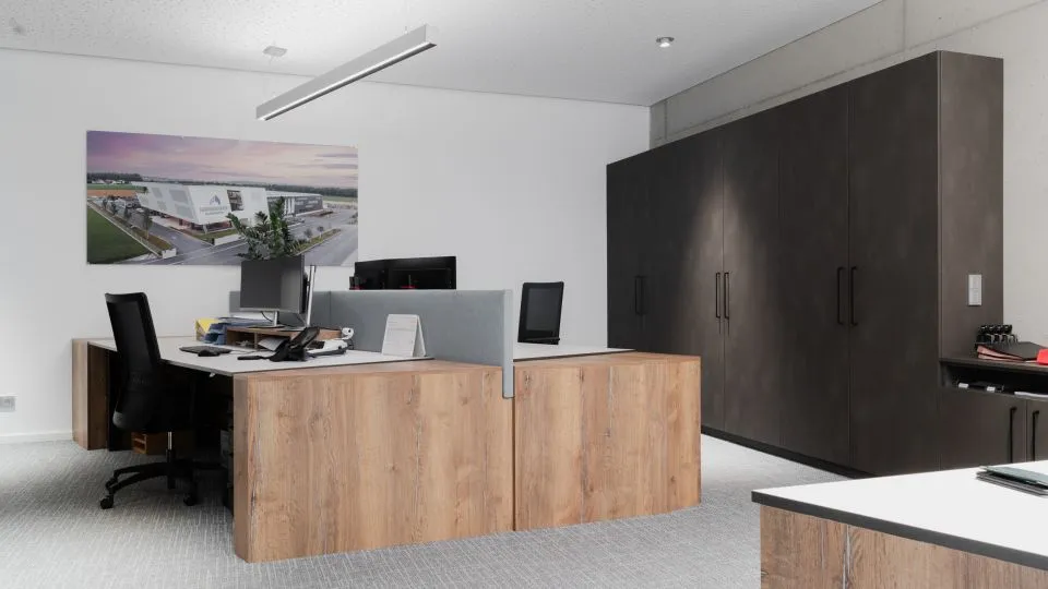 Büro mit Schreibtisch, Bildschirmen und Hochschränken