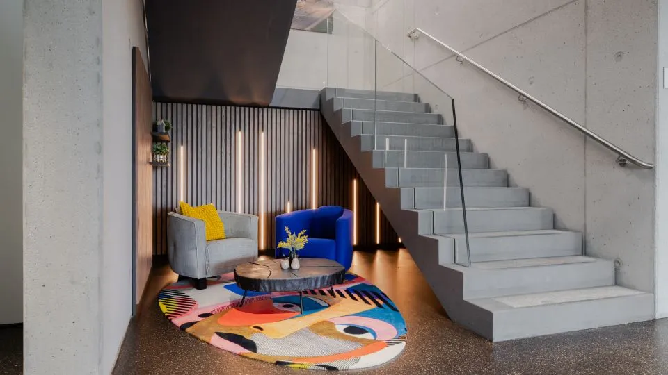 Sitzecke mit Sesseln und buntem Teppich unter der Treppe