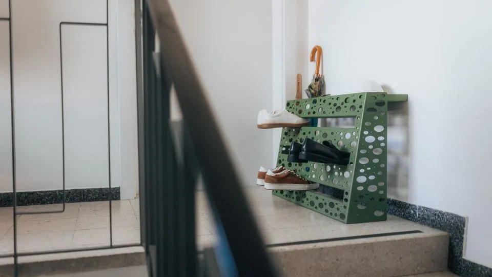 Grünes Schuhregal neben einer Treppe