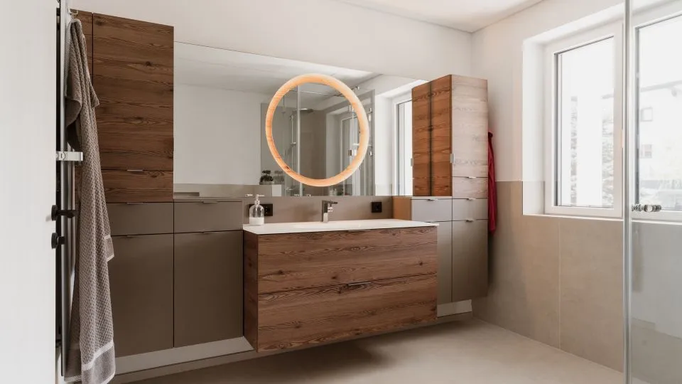 Badezimmer mit Waschtisch aus Altholz und rundem beleuchtetem Spiegel