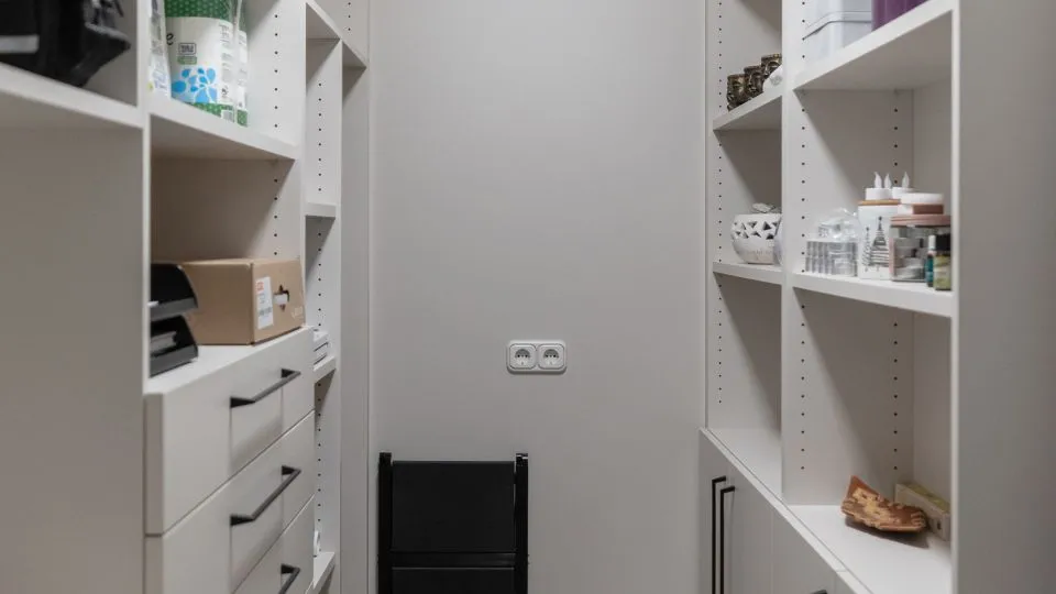 Begehbare Speisekammer mit weißen Regalen, Schubladen und Vorräten