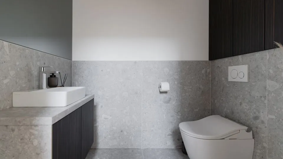 Badezimmer mit Aufsatzwaschbecken, Steinfliesen und dunklem Unterschrank