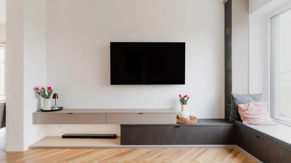 Wohnzimmer mit Wandfernseher, Sideboard und Blick ins Freie