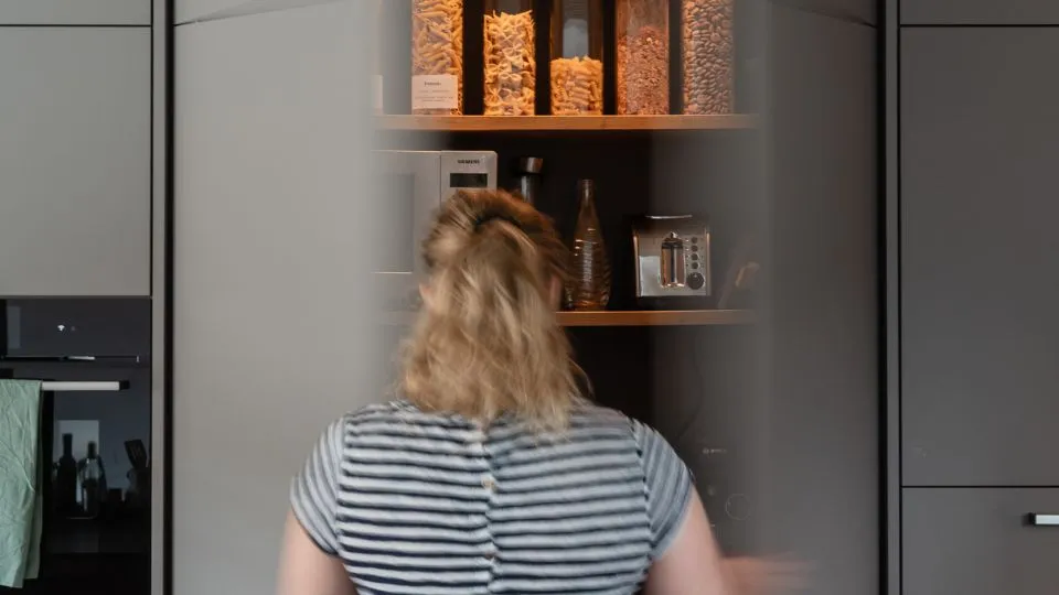 Person vor einem geöffneten Küchenschrank