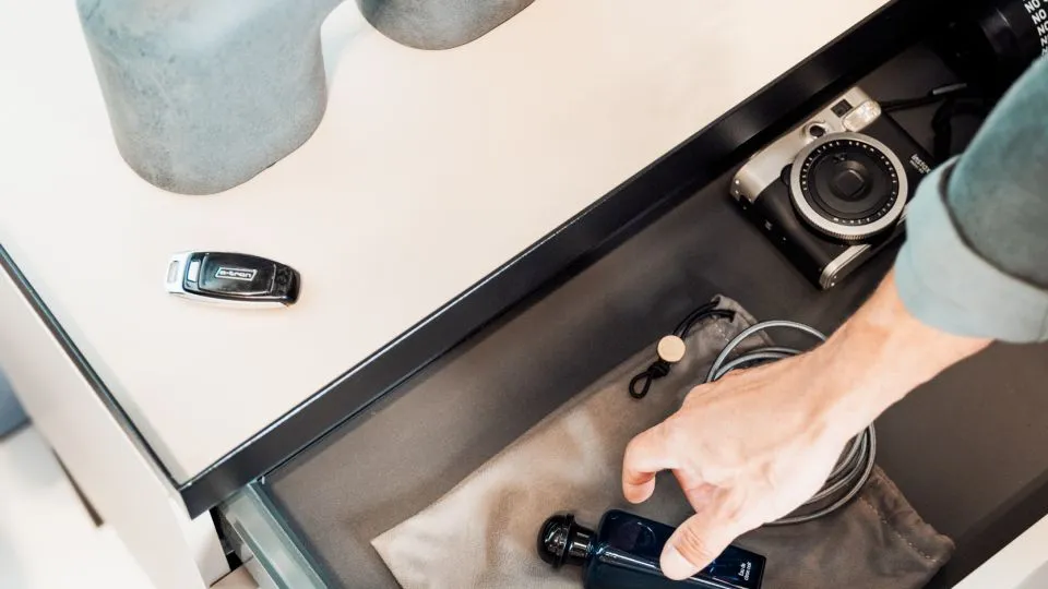 Hand öffnet eine Schublade unter einer Ablage mit Vasen