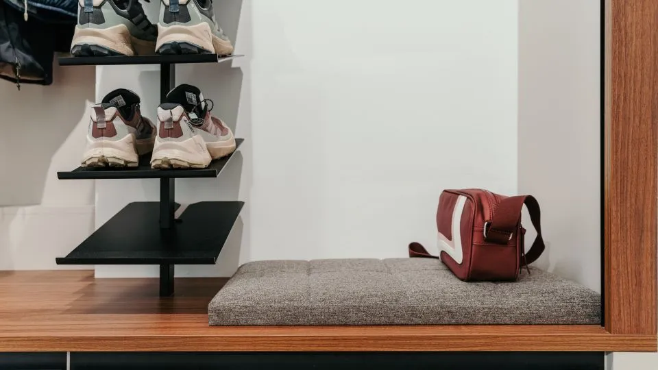 Schuhregal aus schwarzem Metall über einer gepolsterten Sitzbank