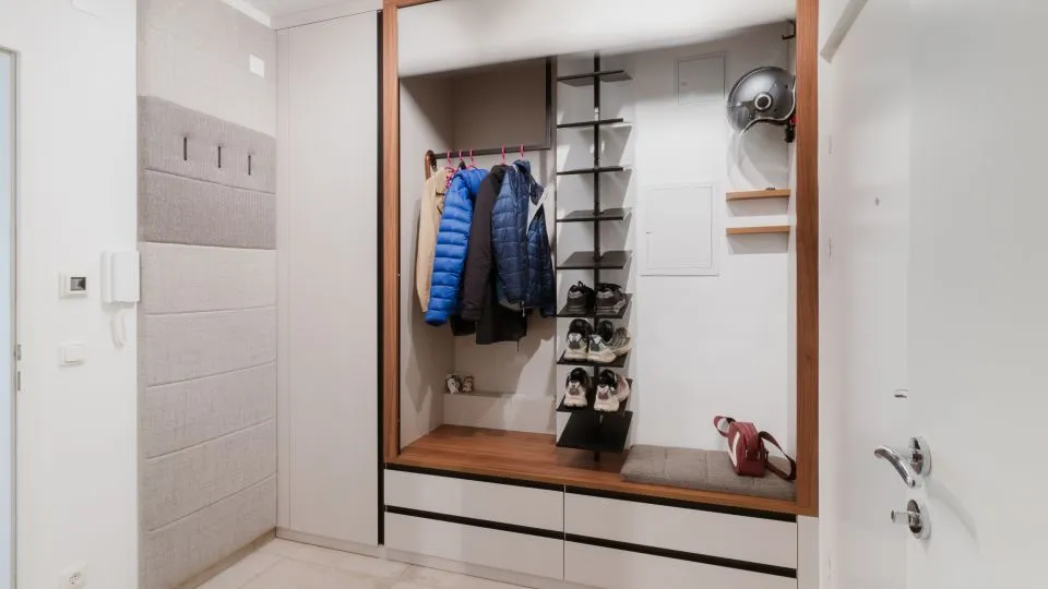Vorzimmer mit geöffneter Garderobennische, Jacken und Schuhen