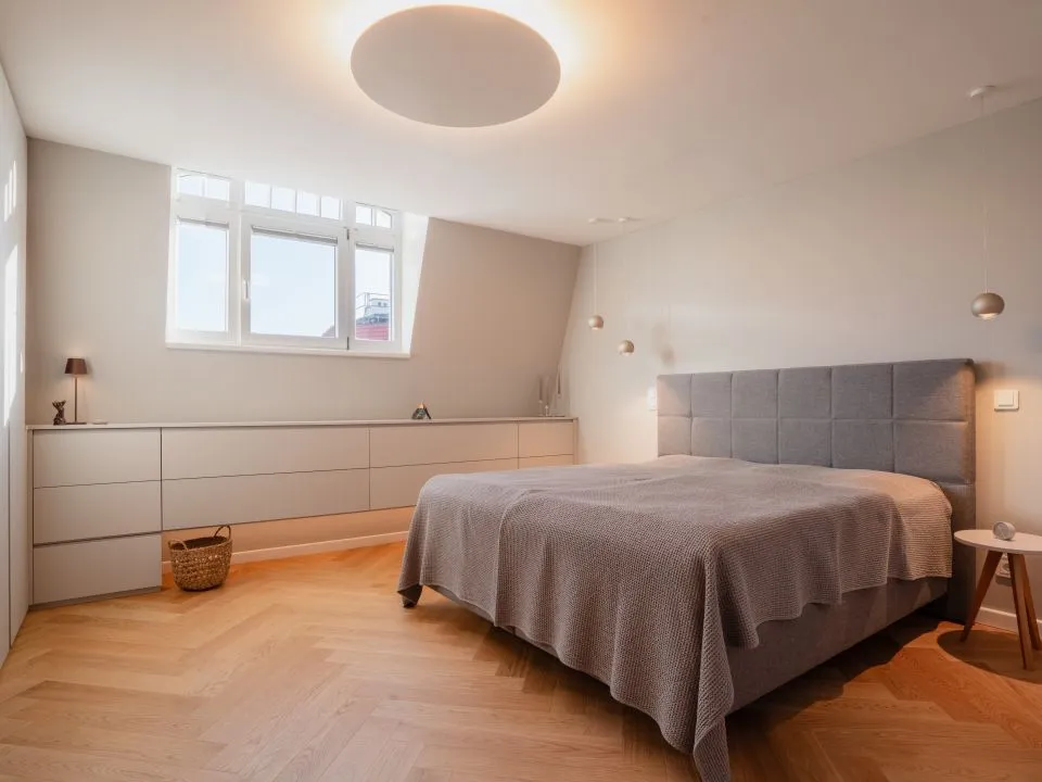 Schlafzimmer unter der Dachschräge mit Bett und Schrankwand