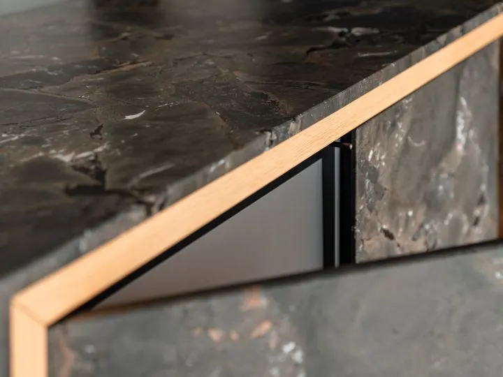 Detail einer dunklen Steinarbeitsplatte mit Holzkante
