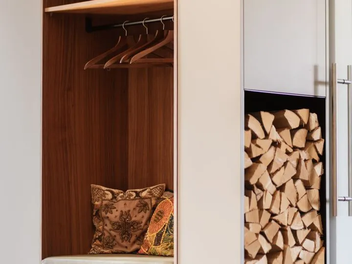 Garderobe mit Kleiderstange neben einem Kaminholzfach