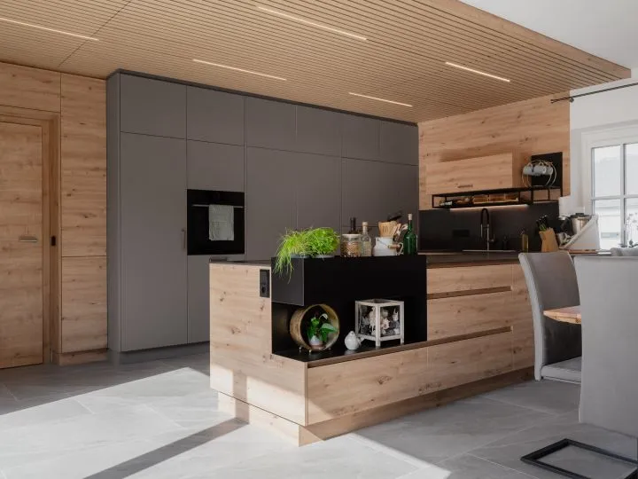 Küche mit Kochinsel, Holzdecke und dunklen Fronten