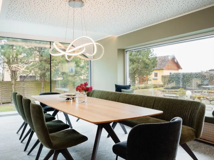 Essbereich mit Holztisch, Designerleuchte und Blick ins Grüne