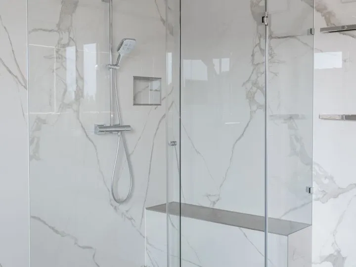 Dusche mit Glaswand und Fliesen in Marmoroptik