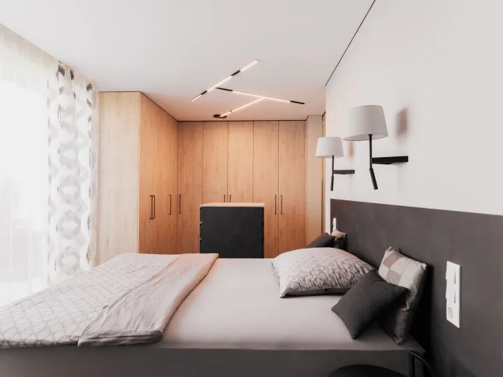Schlafzimmer mit Holzschrank, Polsterbett und Wandleuchten