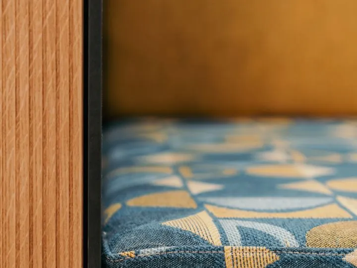 Detail einer Holzkante vor einem unscharfen blau-goldenen Wandbild