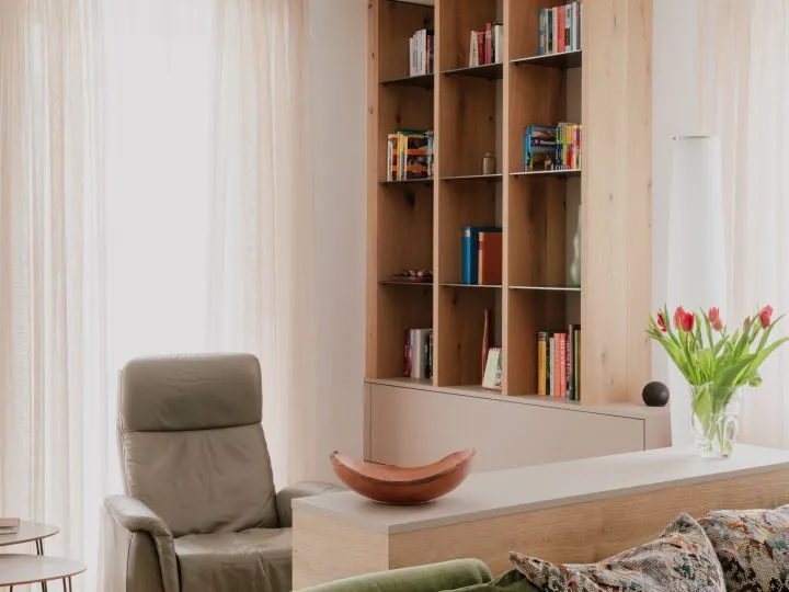 Bücherregal aus Holz mit Sessel und Tulpen davor