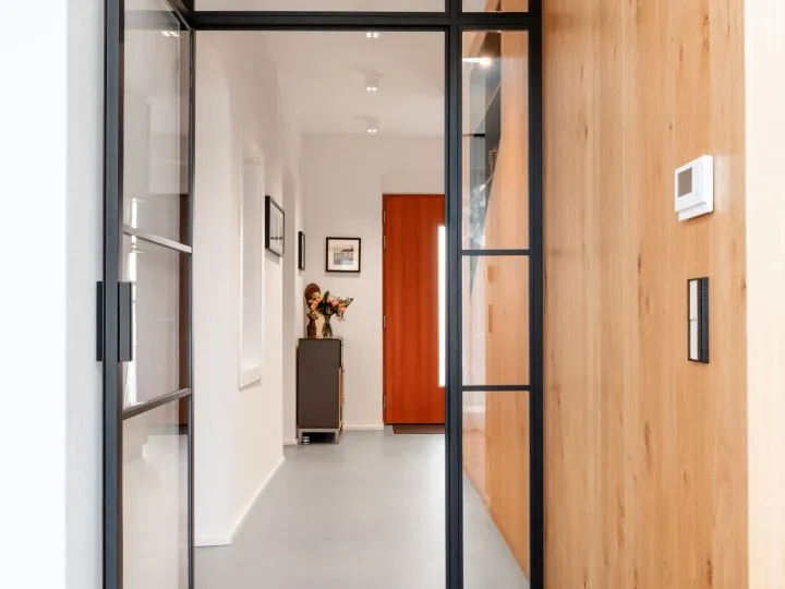 Flur mit Holzverkleidung, Glastür und Sideboard vor roter Wand