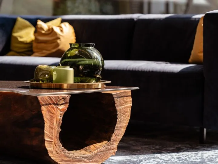 Couchtisch aus Holz mit Vasen und Kerze vor einem dunklen Sofa