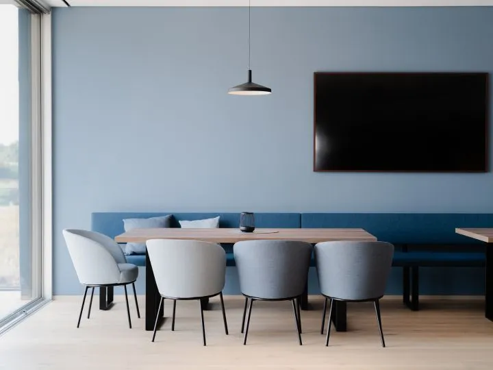 Besprechungsbereich mit blauer Sitzbank, Tisch und Bildschirm