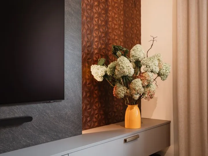 Hortensienstrauß in einer Vase vor gemusterter Wand neben dem Fernseher