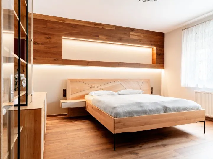 Schlafzimmer mit Holzbett, beleuchtetem Kopfteil und Spiegelschrank