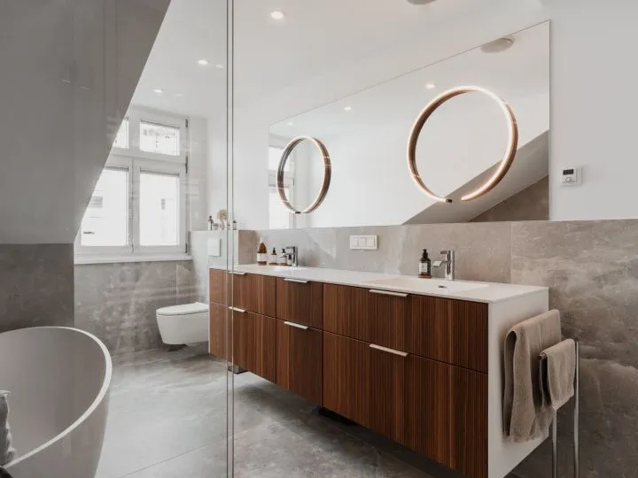Badezimmer unter Dachschräge mit zwei runden Spiegeln und Holzwaschtisch