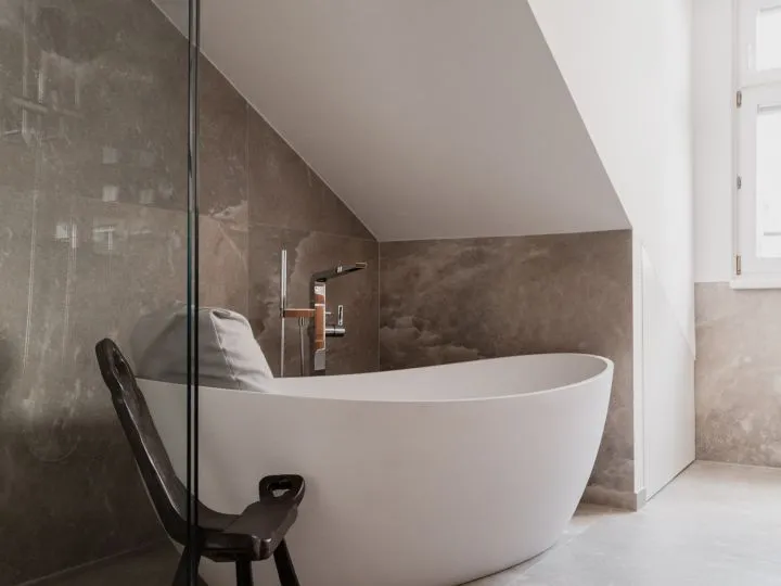 Freistehende Badewanne unter Dachschräge neben einer verglasten Dusche