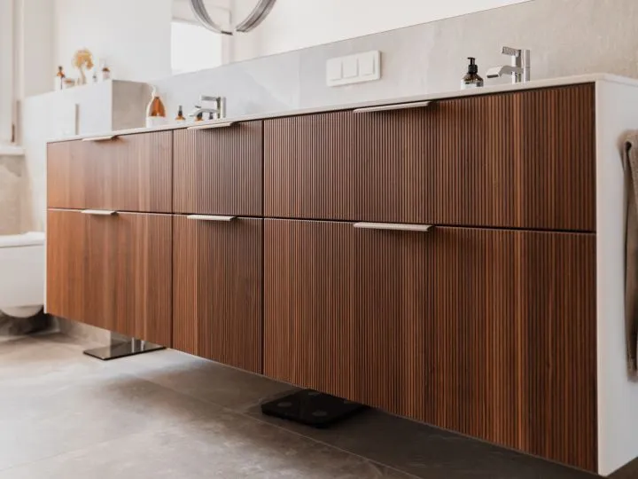 Detail eines Waschtischunterschranks mit vertikaler Rillenstruktur in dunklem Holz
