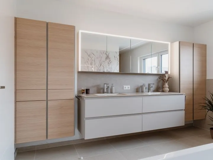 Badezimmer mit Holzschränken, langem Spiegel und Doppelwaschtisch