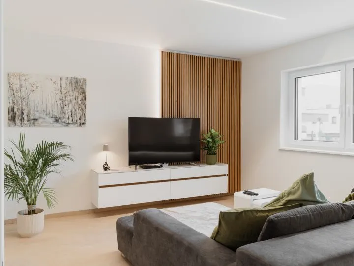 Wohnzimmer mit Fernseher auf weißem Lowboard vor einer Holzlamellenwand