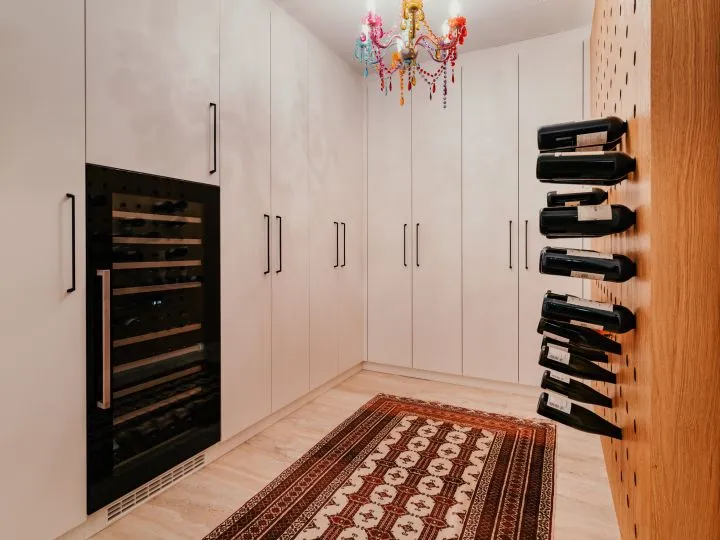 Vorratsraum mit weißen Schränken, Weinklühlschrank und Flaschenregal