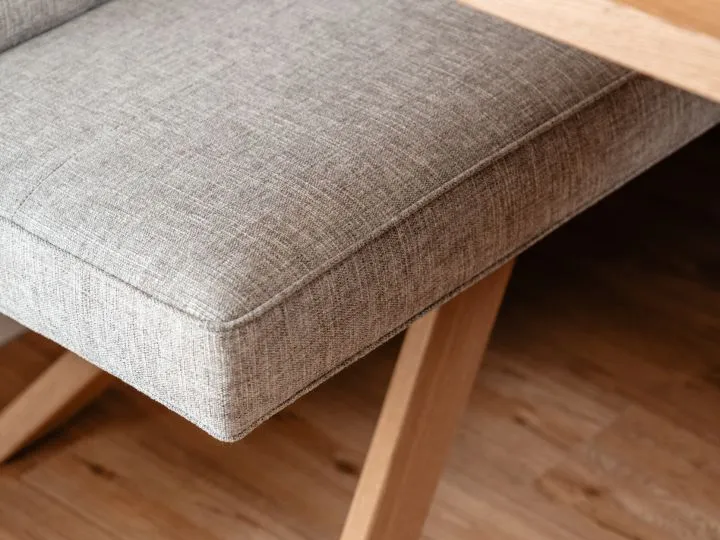 Detail einer Polsterkante aus grauem Webstoff über Holzboden