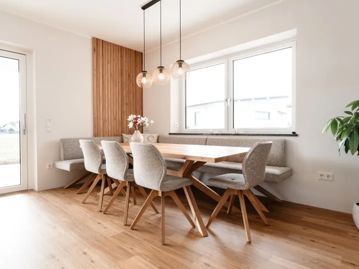 Esszimmer mit Holztisch, Polsterstühlen und Pendelleuchte am Fenster