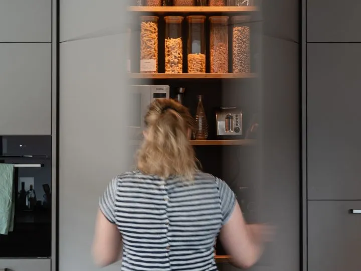 Person vor einem geöffneten Küchenschrank