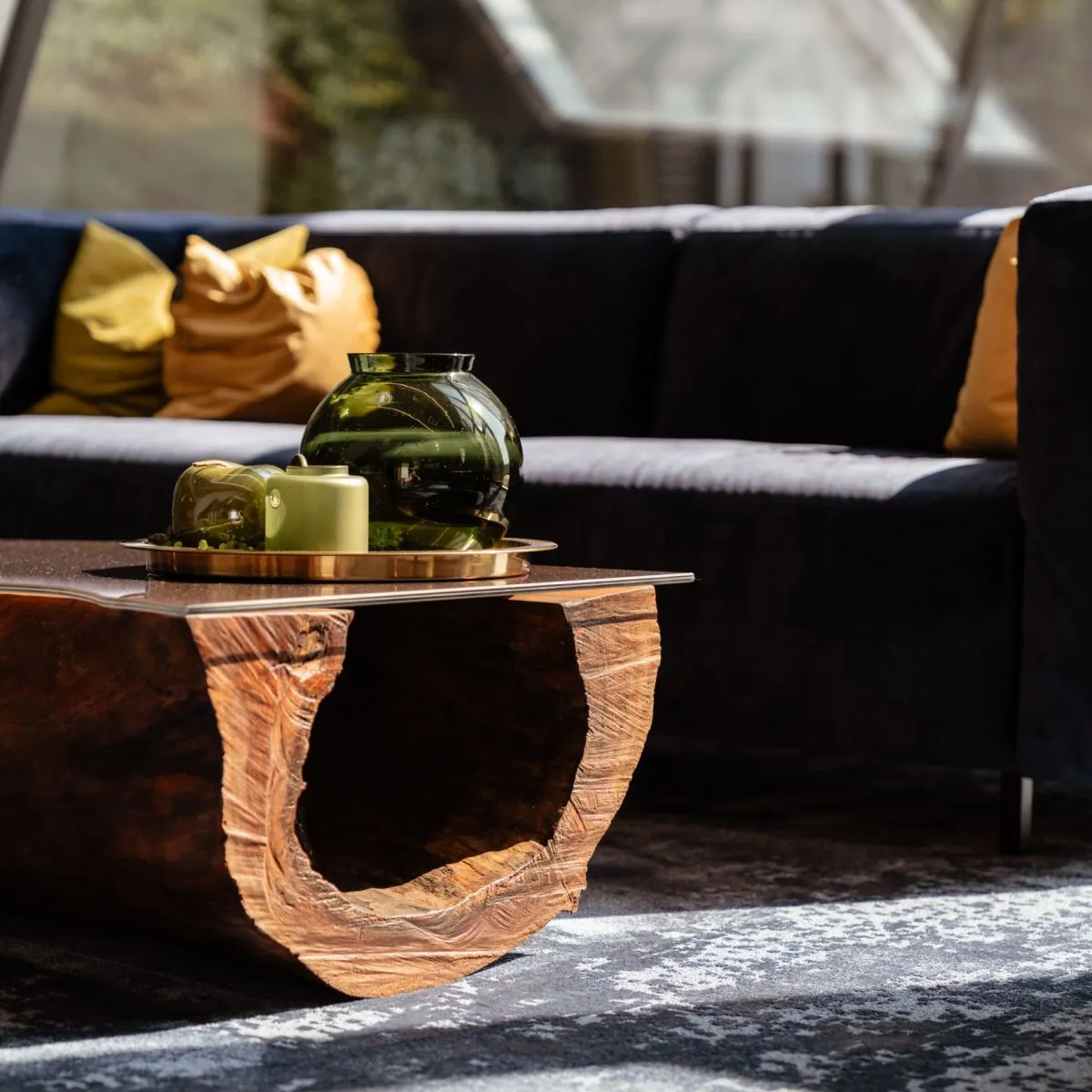 Couchtisch aus Holz mit Vasen und Kerze vor einem dunklen Sofa