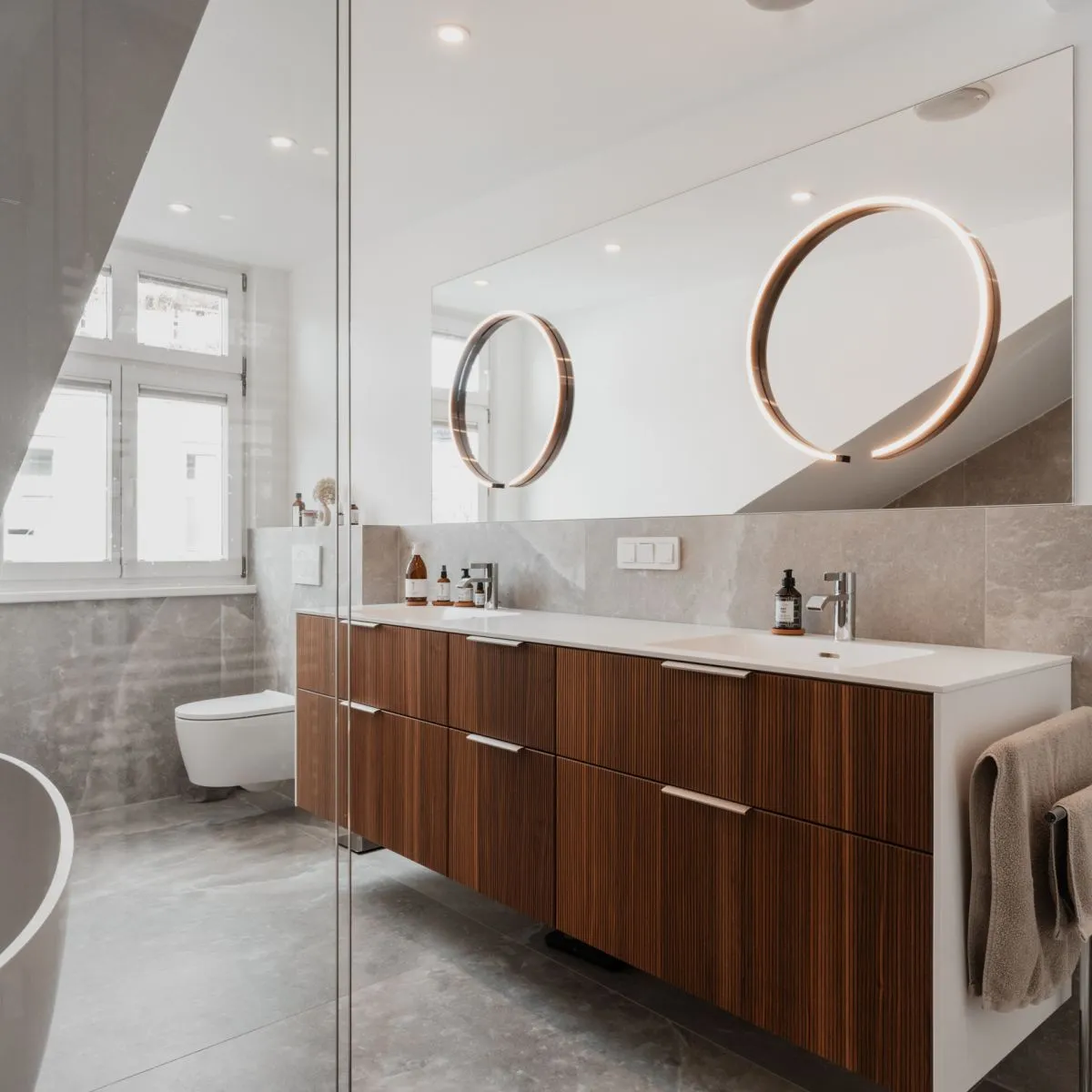 Badezimmer unter Dachschräge mit zwei runden Spiegeln und Holzwaschtisch