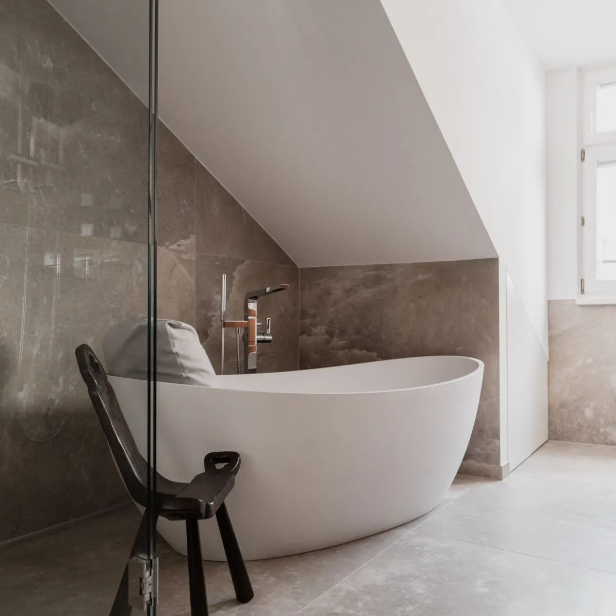 Freistehende Badewanne unter Dachschräge neben einer verglasten Dusche